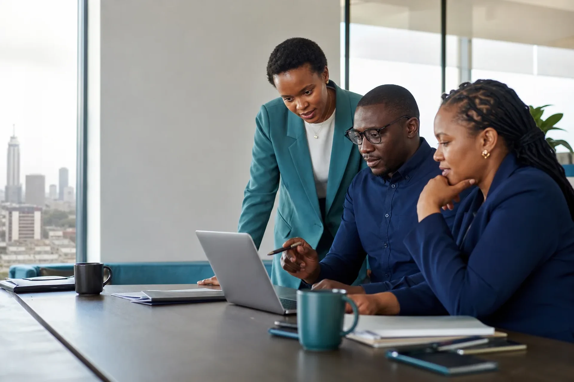 A Contlant team reviewing figures on a laptop, with the Nairobi skyline visible through the office window