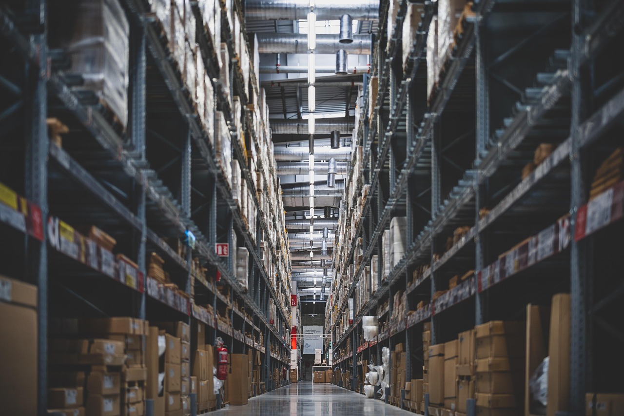 A tall warehouse aisle stacked with shelved cartons, seen down its length