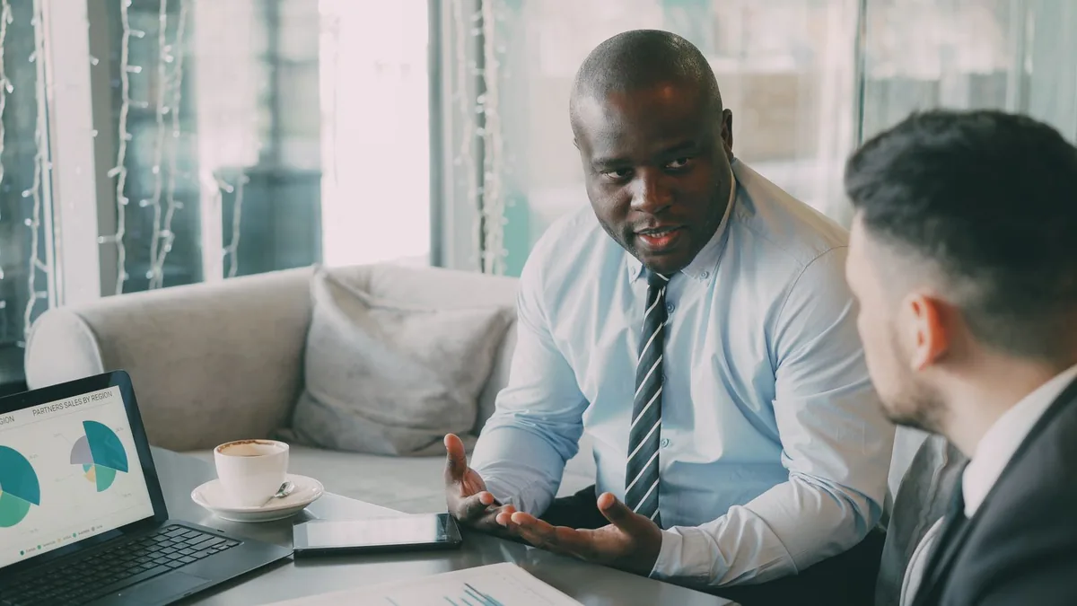 An adviser talking a client through figures shown on a laptop
