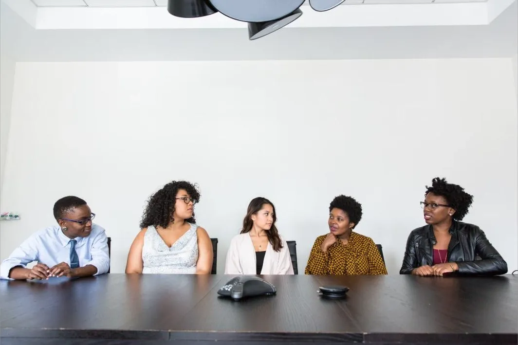 Five colleagues at a conference table in discussion